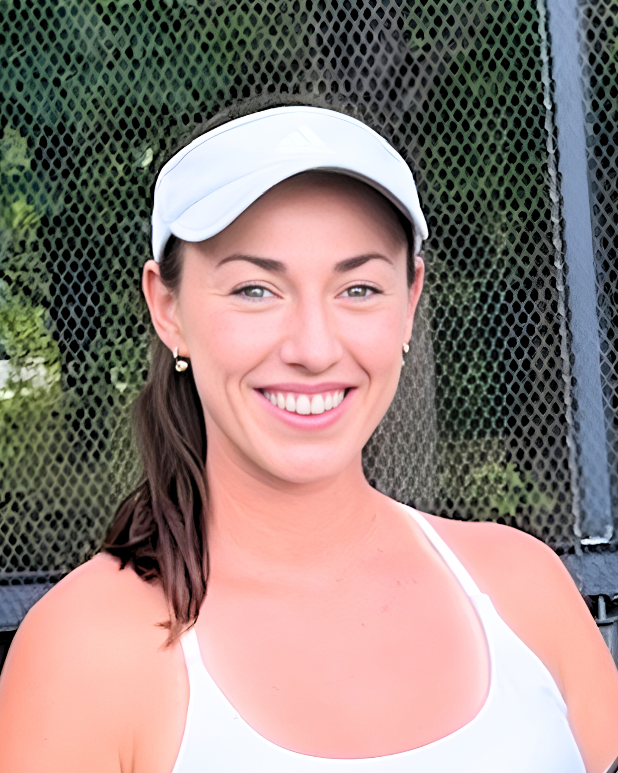 Person wearing a white visor and athletic top standing in front of a mesh fence outdoors.
