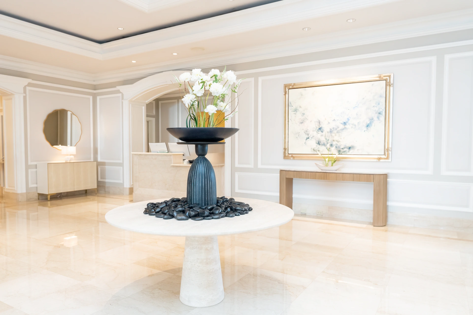 Elegant eau palm beach lobby with marble floors, a round centerpiece table with white flowers, and refined coastal décor.