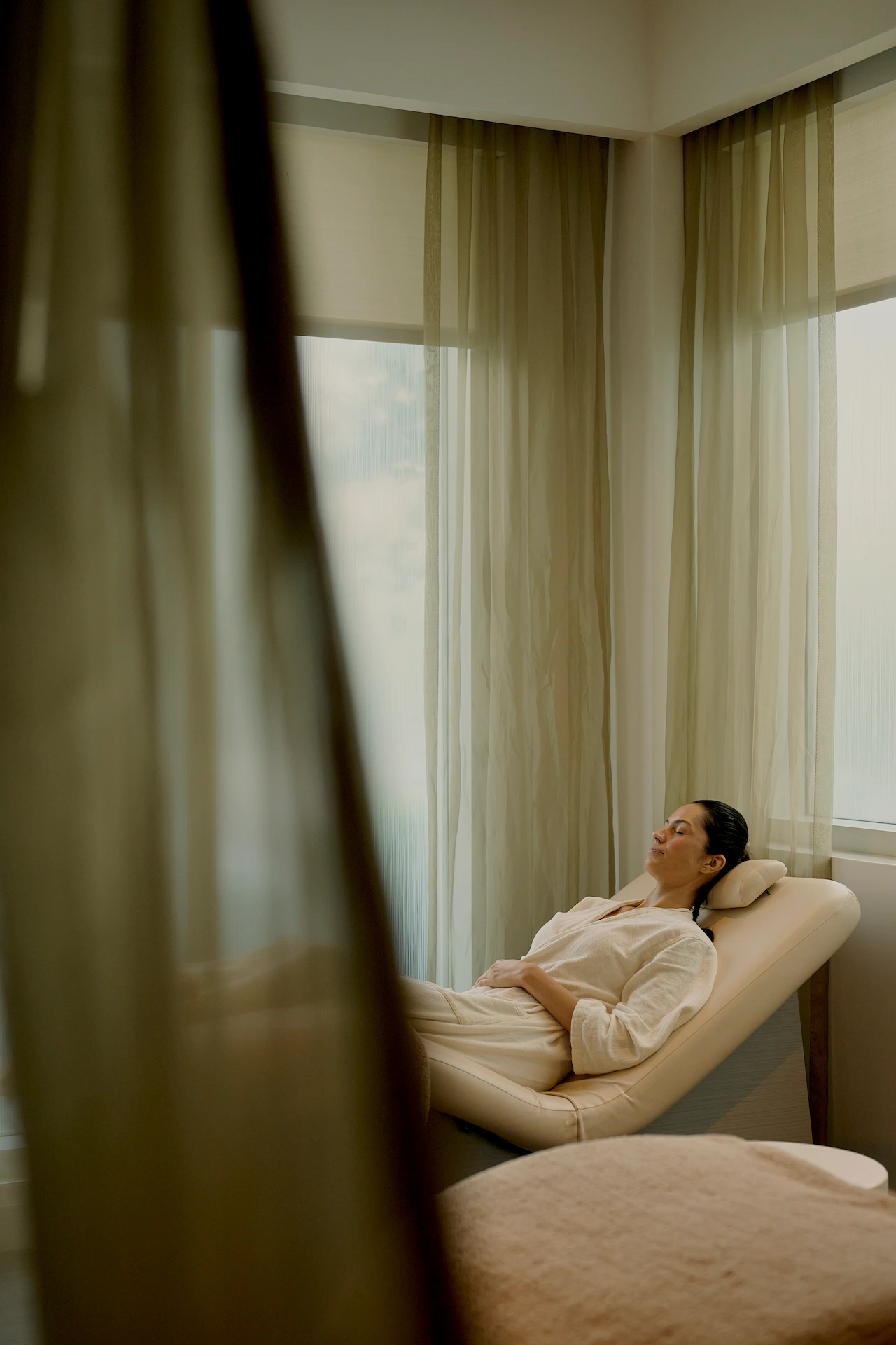 A person resting on a lounge chair in a softly lit room, enjoying a peaceful spa moment.