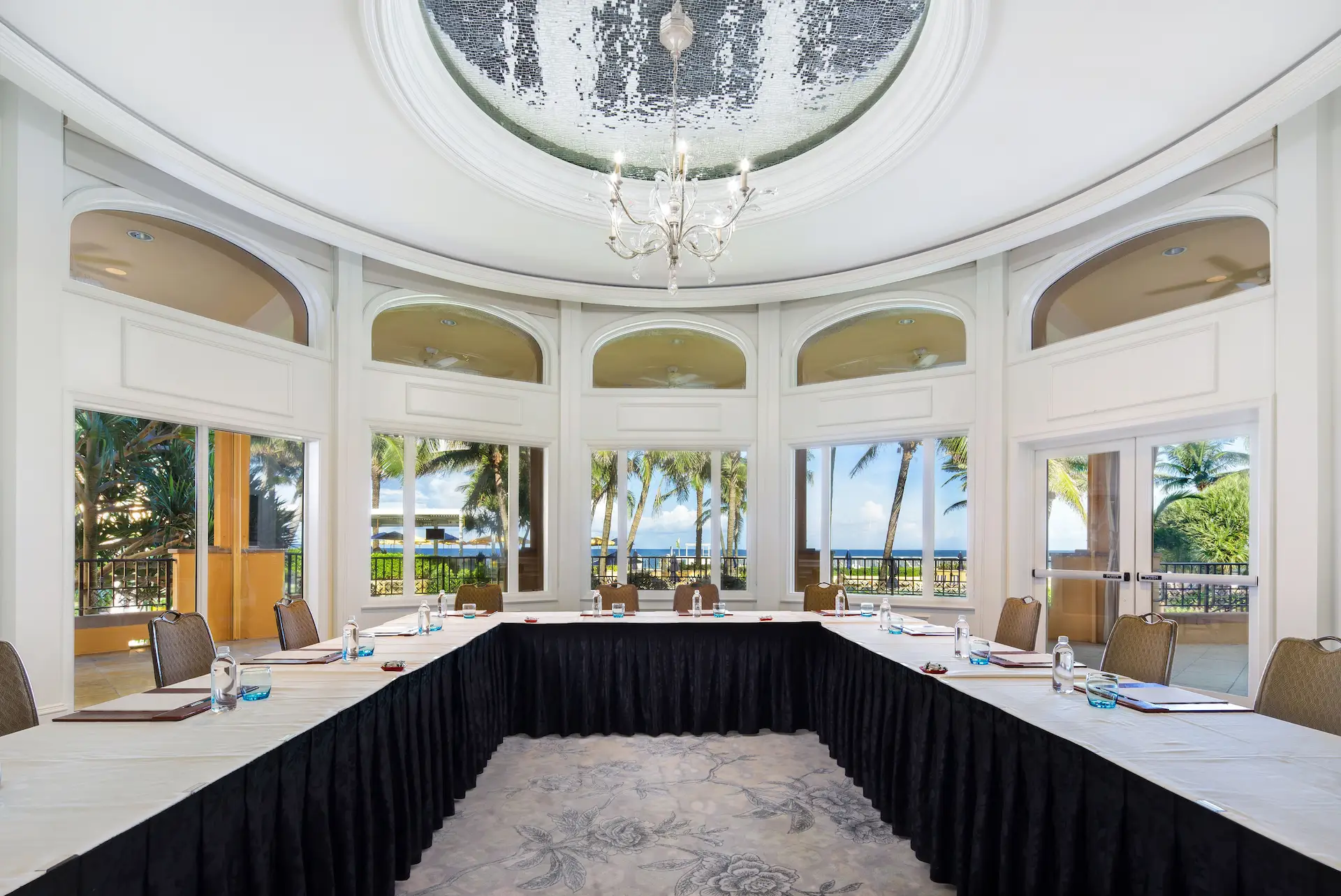 A conference room arranged in a u‑shape with ocean views, natural light, and a refined décor.