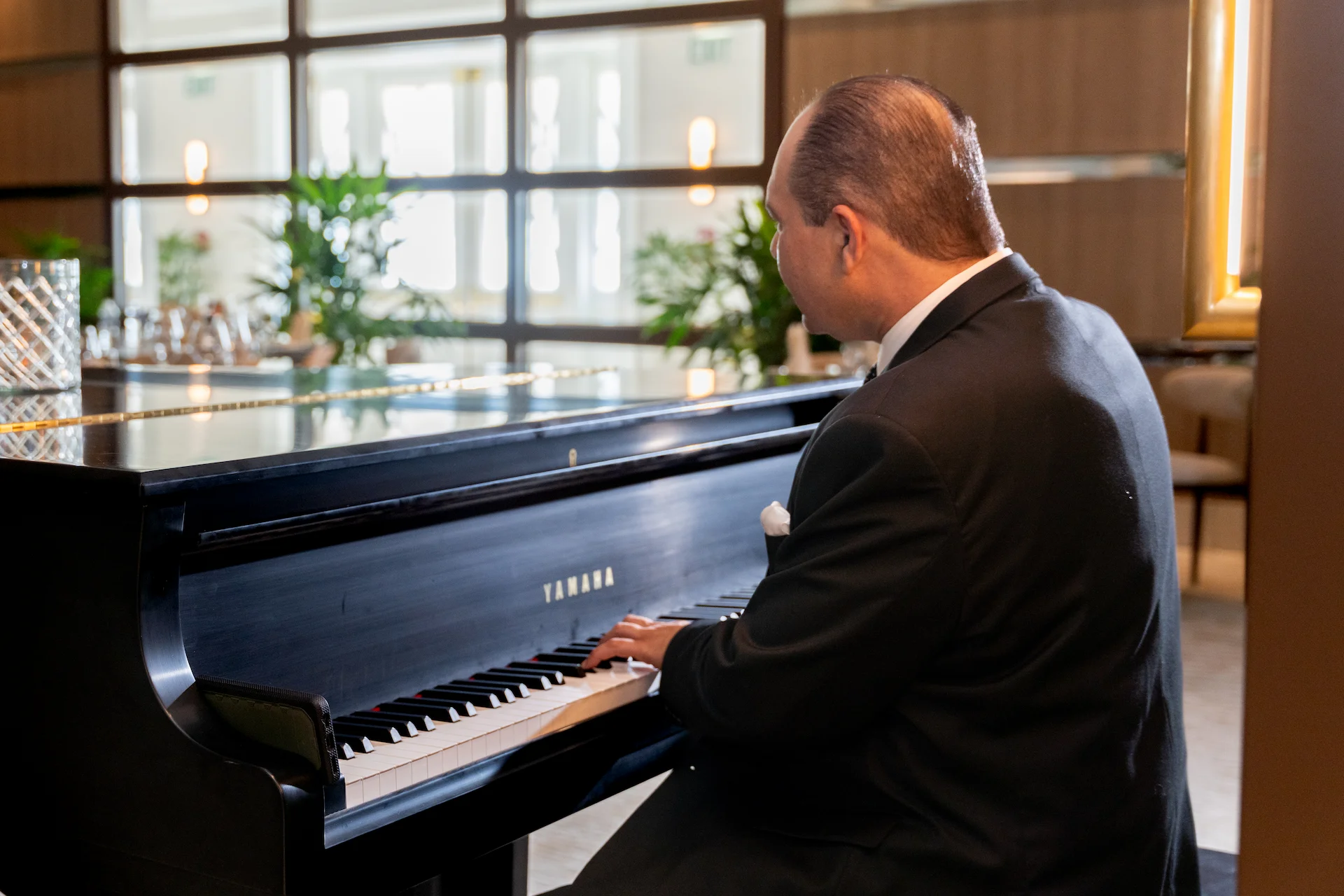 Chad michaels playing a grand piano in an elegant indoor setting.